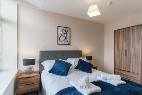 ein Schlafzimmer mit einem großen Bett mit blauen Kissen in der Unterkunft Bright 2 Bed Apartment Manchester - Sleeps 4 in Manchester