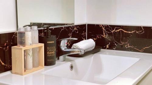 lavabo con grifo y artículos de aseo en Waikato Uni guest room with private bathroom en Hamilton