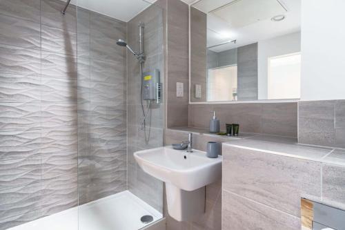 een witte badkamer met een wastafel en een douche bij Modern Manchester Studio Near Old Trafford in Manchester