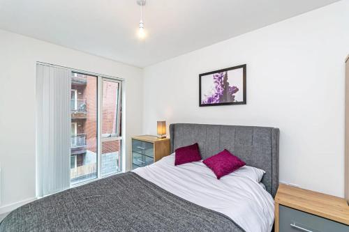 um quarto com uma cama com almofadas roxas e uma janela em Contemporary 2 Bed Apartment in Central Manchester em Manchester