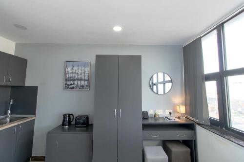 a kitchen with a sink and a desk with a mirror at Lovely Central Sunderland Budget Studio in Sunderland