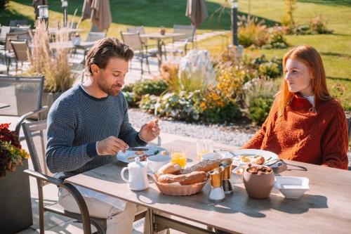 a man and woman sitting at a table eating food at Hotel Sperlhof in Windischgarsten