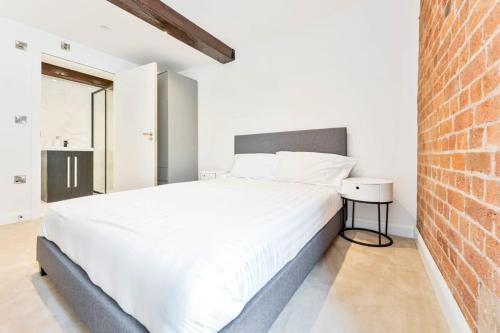 um quarto com uma cama branca e uma parede de tijolos em Characterful 1 Bed Apartment in Burton-on-Trent em Burton upon Trent
