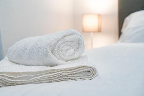 a pile of towels sitting on top of a bed at Modern and Bright 1 Bed Apartment Dudley in Brierley Hill