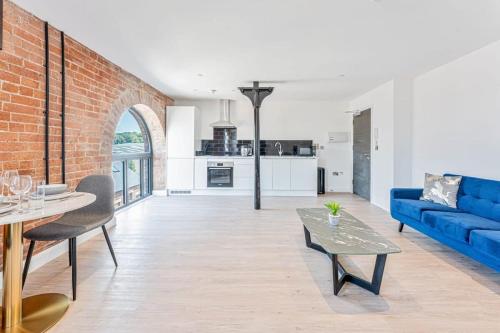 ein Wohnzimmer mit einem blauen Sofa und einer Ziegelwand in der Unterkunft Stunning 1 Bed Apartment in Burton-on-Trent in Burton upon Trent