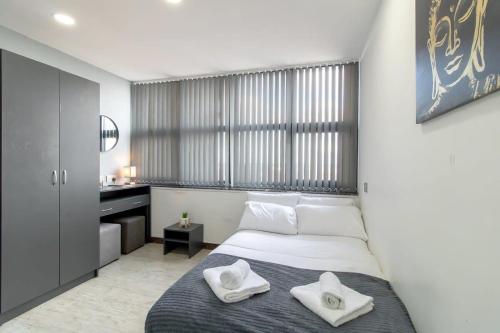 a bedroom with a bed with two white towels on it at Charming Budget Studio in Central Sunderland in Sunderland