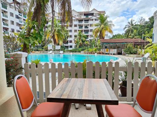 una mesa y sillas frente a una valla con piscina en BAYU BEACH RESORT, en Port Dickson