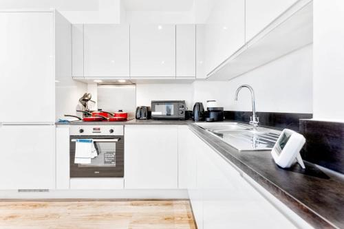 a white kitchen with white cabinets and a sink at Modern and Bright 2 Bed Apartment in Solihull in Birmingham