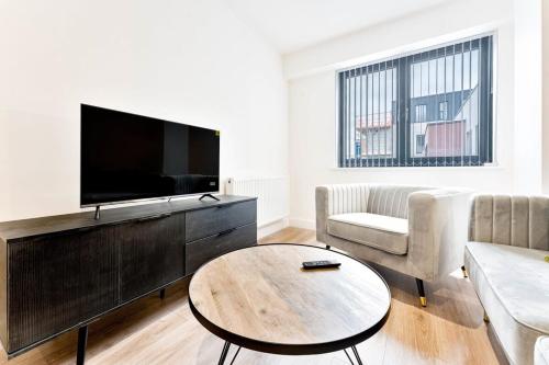 a living room with a tv and a couch and a table at Modern and Bright 2 Bed Apartment in Solihull in Birmingham