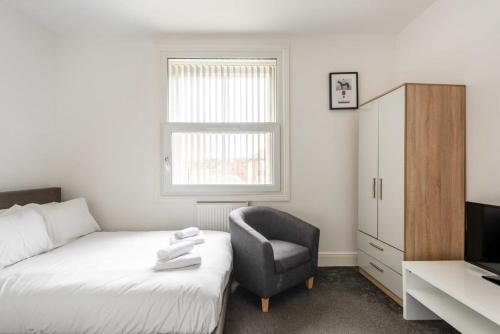 a bedroom with a bed and a chair and a television at Modern and Cosy Budget Studio in Central Doncaster in Doncaster
