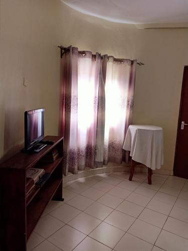 a living room with a table and a television at Nick's and Essy's place in Juja