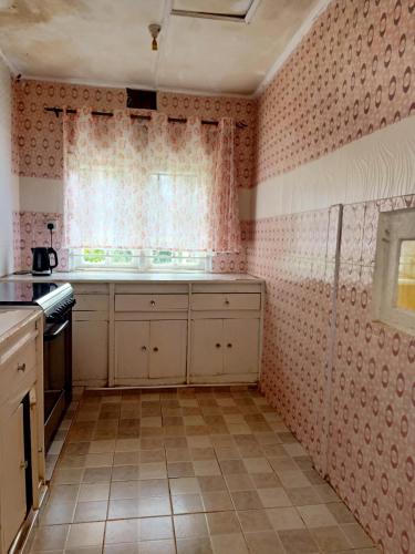 a kitchen with pink patterned walls and a window at Nick's and Essy's place in Juja