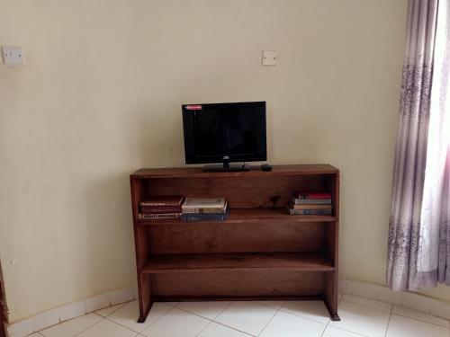 a tv sitting on top of a wooden book shelf at Nick's and Essy's place in Juja