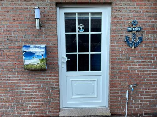 een witte deur op een bakstenen gebouw met een bord bij Ferienhaus Gomann in Dornum
