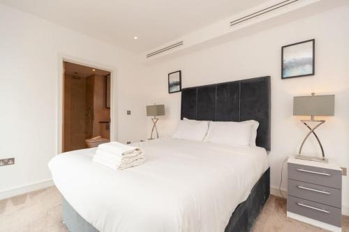 a bedroom with a large white bed with a black headboard at Modern 2 Bed Apartment in South Lambeth in London