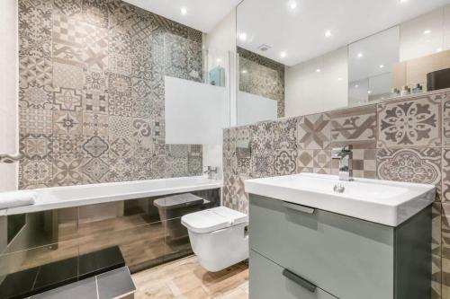 ein Badezimmer mit einem weißen Waschbecken und einem WC in der Unterkunft Stylish 1 Bedroom Apartment in Central Woking in Woking
