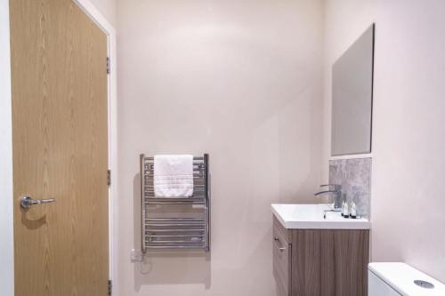 uma casa de banho branca com um lavatório e um toalheiro. em Contemporary 1 Bed Manchester Apartment em Manchester