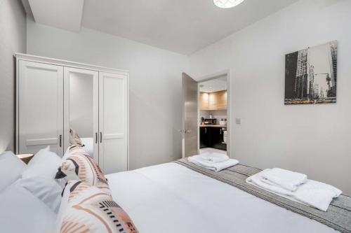 um quarto com uma grande cama branca com almofadas brancas em Stylish 1 Bedroom Apartment in Central Woking em Woking