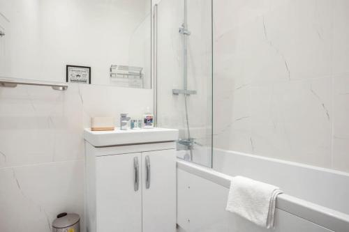 a white bathroom with a shower and a sink at Contemporary 1 Bedroom Apartment in Central Woking in Woking