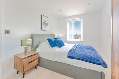 a bedroom with a bed with blue pillows and a night stand at Spacious 2 Bedroom Apartment in Birmingham in Birmingham