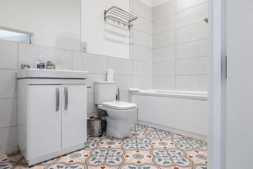 a white bathroom with a toilet and a bath tub at Lovely 1 Bedroom Apartment in Central Woking in Woking