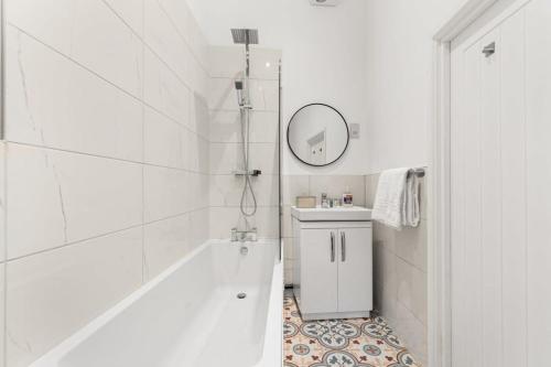 a white bathroom with a tub and a sink at Lovely 1 Bedroom Apartment in Woking Centre in Woking