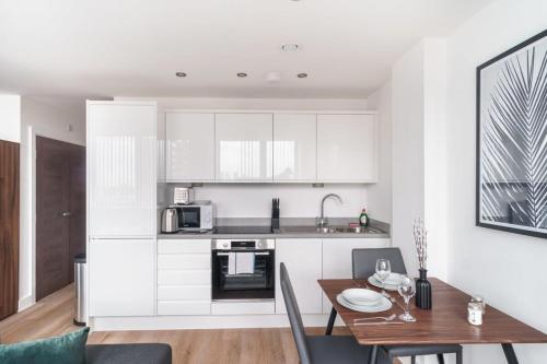 a kitchen and dining room with white cabinets and a table at Stay Zeni, Alexandra Rise Manchester Cosy Studio in Manchester