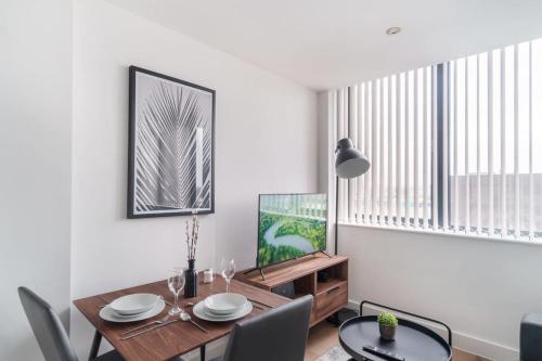 a dining room with a table and chairs and a television at Stay Zeni, Alexandra Rise Manchester Cosy Studio in Manchester
