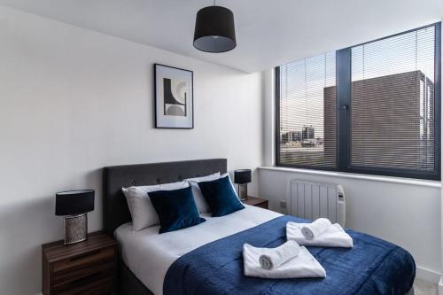 a bedroom with a large bed with towels on it at Bright & Modern 1 Bed Apartment by Old Trafford in Manchester