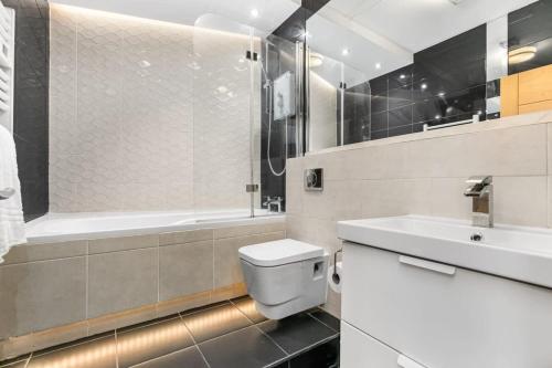 La salle de bains est pourvue de toilettes, d'un lavabo et d'une baignoire. dans l'établissement Spacious 1 Bedroom Apartment in Central Woking, à Woking