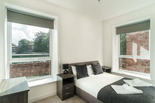 a bedroom with a bed and two large windows at Spacious 3 Bed Apartment in Waterloo Liverpool in Waterloo