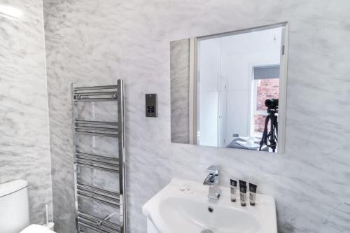een witte badkamer met een wastafel en een spiegel bij Spacious 3 Bed Apartment in Waterloo Liverpool in Waterloo