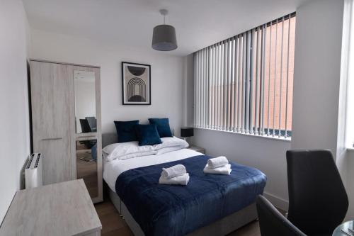Fantastic Studio Apartment by Old Trafford في مانشستر: غرفة نوم بسرير وملاءات زرقاء وطاولة