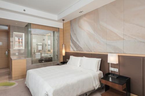a bedroom with a large white bed and a bathroom at Hai Tian Expo Hotel in Qingdao