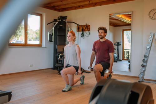 a man and a woman in a gym with weights at Hotel Sperlhof in Windischgarsten