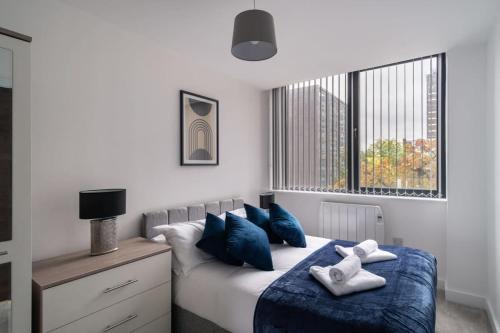 - une chambre avec un lit doté d'oreillers bleus et d'une fenêtre dans l'établissement Lovely 1 Bedroom Apartment in Old Trafford, à Manchester