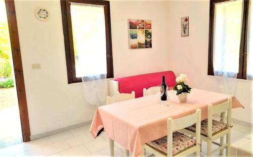 a dining room with a table and a bottle of wine at Ferienhaus Casa Geranio - Villaggio Galanu in Costa Paradiso