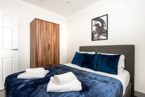 a bedroom with a blue bed with towels on it at Smart 1 Bedroom Apartment in Leeds in Leeds