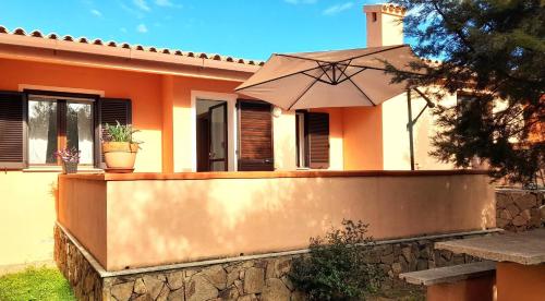a house with an umbrella in front of it at Ferienhaus Casa Oliva - Villaggio Galanu in Costa Paradiso