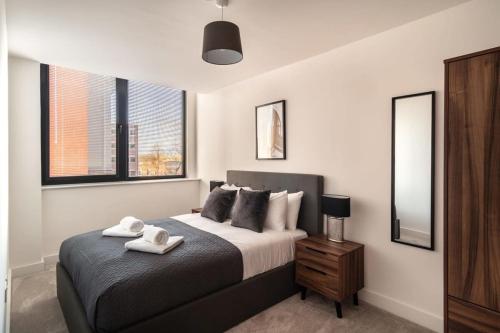 1 dormitorio con 1 cama con 2 toallas en Modern & Spacious 2 Bed Apartment by Old Trafford, en Mánchester