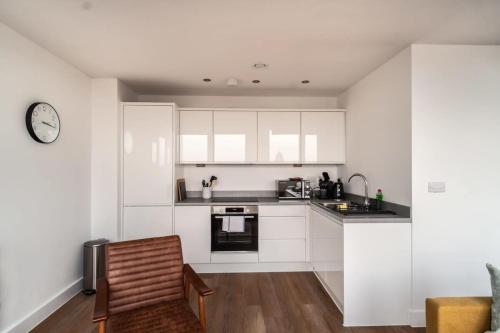 a kitchen with white cabinets and a clock on the wall at StayZeni, Alexandra Rise Manchester Super 1 Bed in Manchester