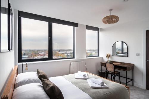 a bedroom with a bed and a desk and windows at Sleek 1 Bedroom Apartment by Old Trafford in Manchester