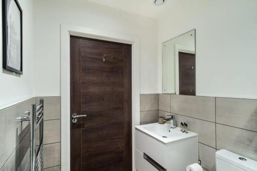 a bathroom with a sink and a wooden door at Sleek 1 Bedroom Apartment by Old Trafford in Manchester