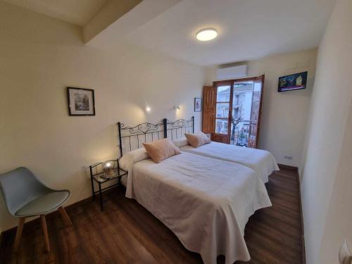 - une chambre avec un grand lit et une chaise dans l'établissement Los Cuatro Caños, à Madrigal de la Vera
