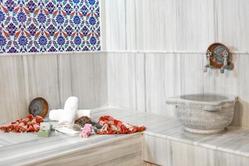 um quarto branco com uma mesa com flores e um lavatório em Olbios Marina Resort Hotel em Kumkuyu
