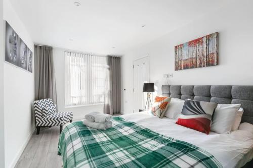 a bedroom with a bed with a green and white blanket at Smart 1 Bedroom Apartment in Central Woking in Woking