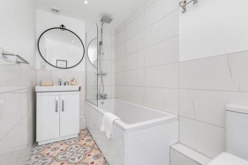 ein weißes Badezimmer mit einer Badewanne und einem Waschbecken in der Unterkunft Smart 1 Bedroom Apartment in Central Woking in Woking