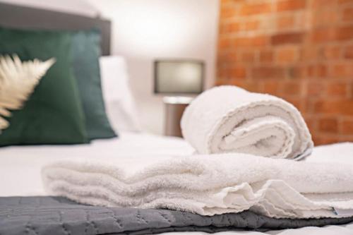 a pile of towels on top of a bed at Lovely 1 Bed Apartment in Burton-on-Trent in Burton upon Trent