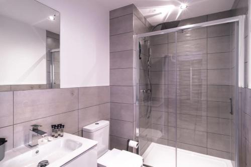 uma casa de banho com um chuveiro, um WC e um lavatório. em Smart Studio Apartment by Old Trafford em Manchester