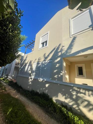 uma casa branca com a sua sombra ao lado dela em Centrum Almyrida Apt em Almirída